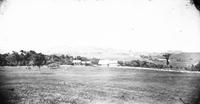 House and barns across a field with rolling hills and fields in the                        background.