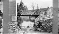 Man leaning against a building next to a stream and dam