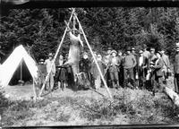 Deer hanging upside down surrounded by hunters