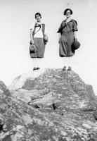 Two women with hats atop a rock