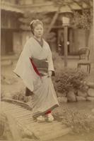 Woman crossing bridge over pond