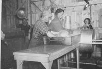 Workers washing collection buckets inside sugar house