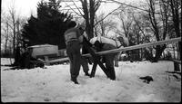 Workers arranging metal piping to transport maple sap to collection tank