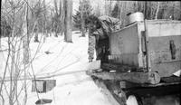 Worker arranging metal piping to transport maple sap to collection tank